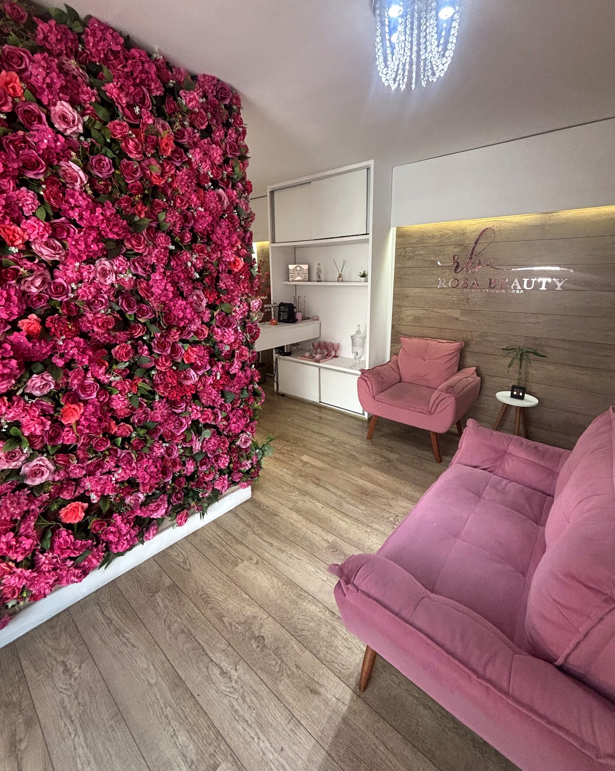Recepção da Rosa Beauty Space em Alphaville com parede de flores e poltronas rosé